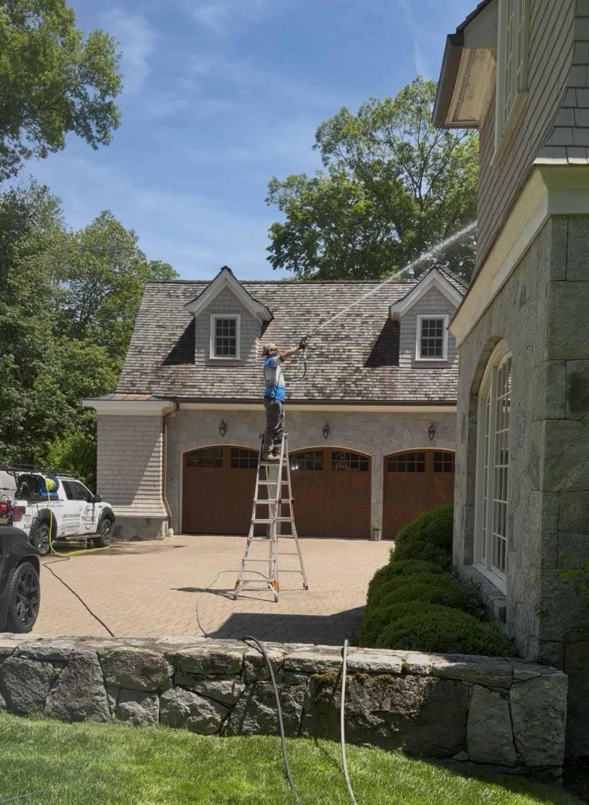 Crew on ladders cleaning windows on a stone house
